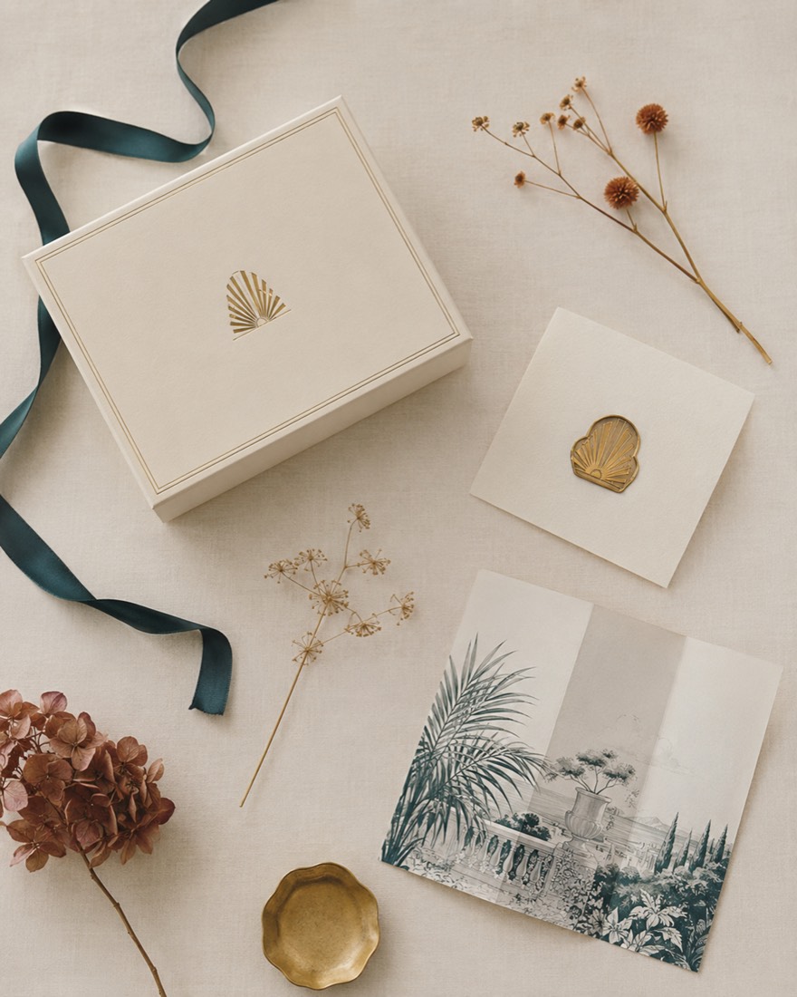 An ivory gift box, ribbon and illustrated insert being wrapped